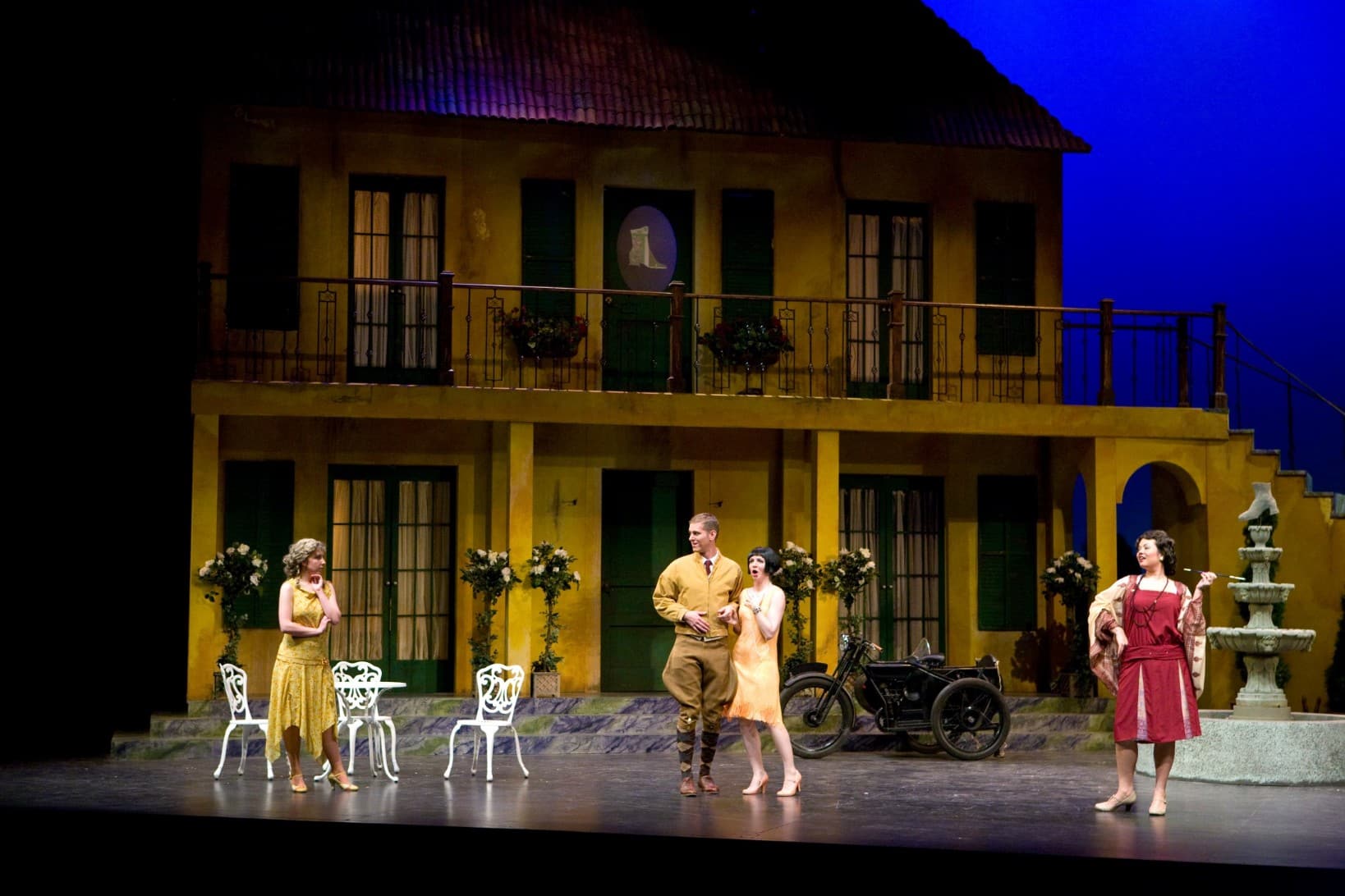 Sarah at center stage in a black wig next to a man. Two women are standing on either side of them, one with a look of amusement
on her face.