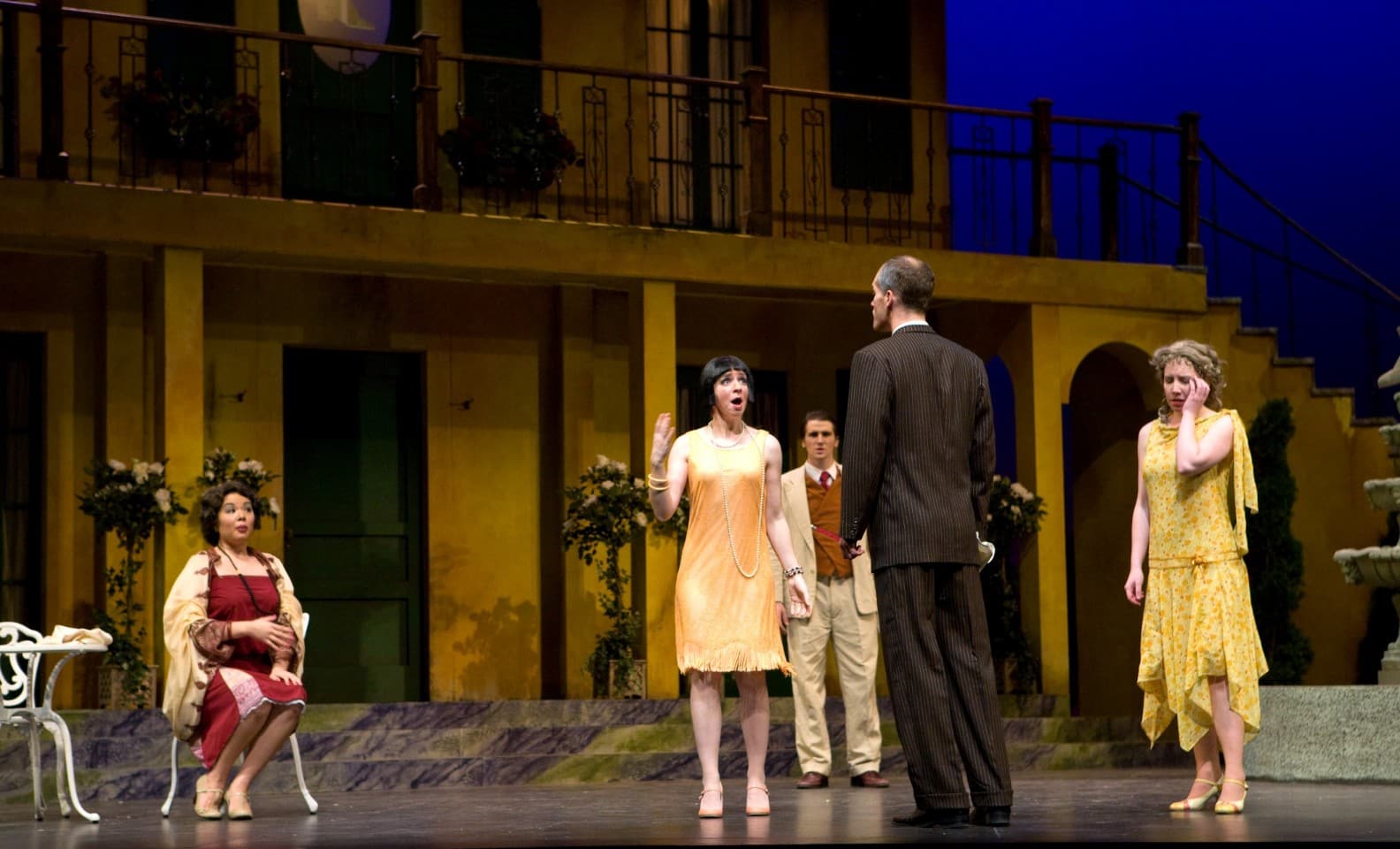 a man has his back to the audience, and Sarah, whose face is to the audience, is singing to him. Other characters on stage
look distressed.