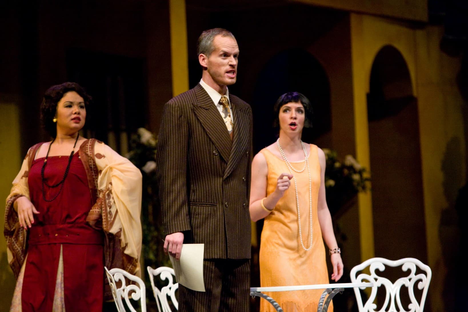 A man is standing holding a paper in one hand with an intense look on his face. A proud woman stands behind him, and a concerned
woman stands to the side